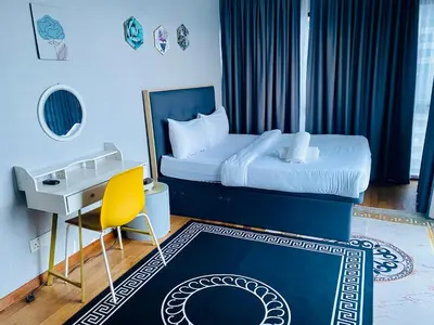 a bedroom with a bed with a desk and a yellow chair at Supper Suite By Reizz Residence in Kuala Lumpur