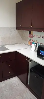 a kitchen with brown cabinets and a white counter top at BTS apartment at times square in Kuala Lumpur