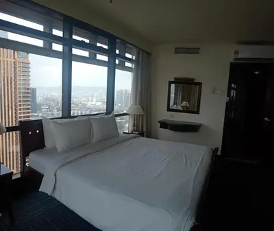 a bedroom with a white bed and a large window at BTS apartment at times square in Kuala Lumpur