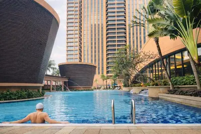 a man in a swimming pool in front of buildings at Signature Stay Times Square, Kuala Lumpur in Kuala Lumpur