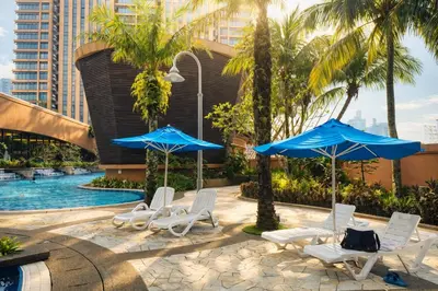 a pool with lounge chairs and umbrellas and a pool at Signature Stay Times Square, Kuala Lumpur in Kuala Lumpur