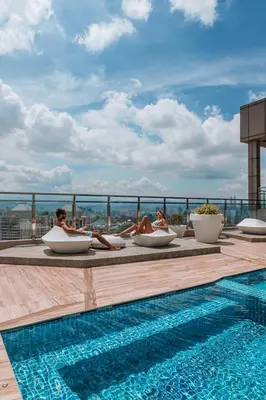 two women sitting in chairs next to a swimming pool at Dorsett Hartamas with Rooftop Pool and Bathtub in KL City #215 in Kuala Lumpur
