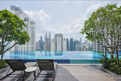a large swimming pool with chairs and a city skyline at KL Majestic VIP studio Massage Chair 26-1A KLCC view in Kuala Lumpur