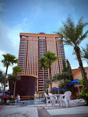 a tall building with white chairs and palm trees at Residential Family Apartments At Times Square KL in Kuala Lumpur