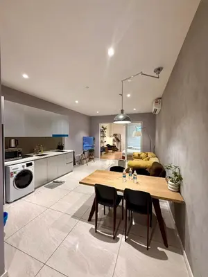 a kitchen and living room with a wooden table and chairs at Kualalumpur Quill Residences Suites By KLCC in Kuala Lumpur