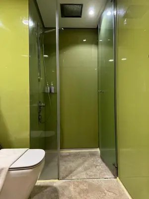 a green bathroom with a toilet and a shower at Sky Suites KLCC Luxury Cozy Suites in Kuala Lumpur