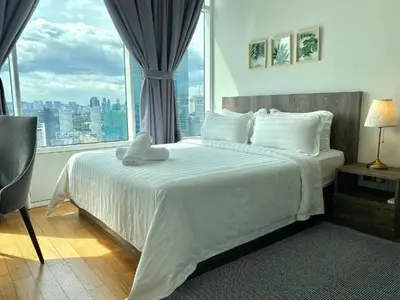a bedroom with a white bed with a large window at Sky Suites KLCC Luxury Cozy Suites in Kuala Lumpur