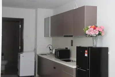 a kitchen with a black refrigerator and a vase of flowers at Regalia SkyPool8 in Kuala Lumpur