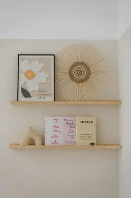 a shelf with two pictures and a mirror and books at Cozy Cityscape Homestay in KL City Center 1-5pax in Kuala Lumpur