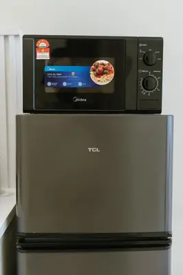 a microwave oven sitting on top of a refrigerator at Cozy Cityscape Homestay in KL City Center 1-5pax in Kuala Lumpur