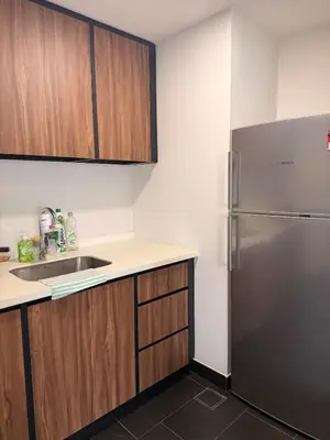 a kitchen with a stainless steel refrigerator and wooden cabinets at UNA Residence Maluri MRT Velocity TRX Bkt Bintang in Kuala Lumpur
