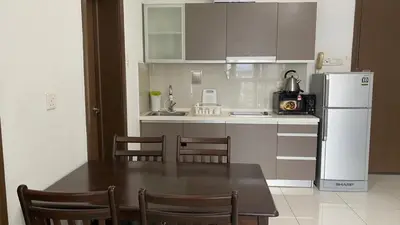 a kitchen with a table and a white refrigerator at Regalia skypool8 in Kuala Lumpur