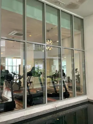 a gym with mirrored windows and people exercising on tread machines at Regalia skypool8 in Kuala Lumpur