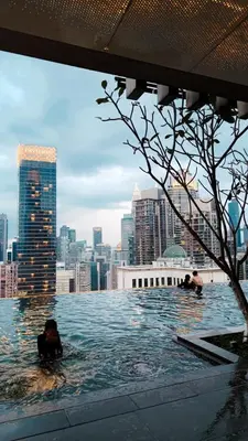 two people swimming in a swimming pool in a city at Axon premier suites, Pavilion Bukit bingtang, KL Tower in Kuala Lumpur