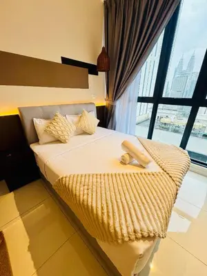 a bed in a room with a large window at Majestic Residence klcc by Stay Suites in Kuala Lumpur