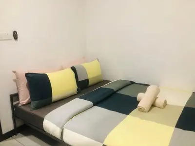 a bed with colorful pillows on it in a room at Neu Suites Apartment - Cozy Modern Stay near KLCC in Kuala Lumpur