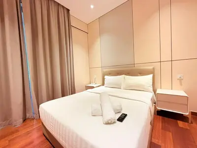 a bedroom with a white bed with a remote control on it at The Manor Kuala Lampur in Kuala Lumpur