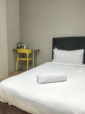 a white bed with a pillow and a yellow table at Ocean 77 by Pillow Plus Petaling Street KL in Kuala Lumpur
