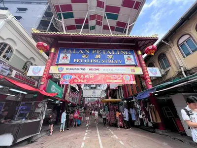 a building with a sign on a street with people walking around at Amigo Petaling Street Kuala Lumpur in Kuala Lumpur