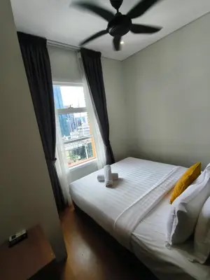 a bedroom with a bed with a ceiling fan and a window at Sky Suites KLCC by Tareen Haven suites in Kuala Lumpur