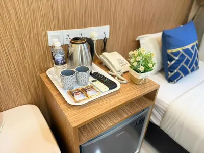 a table with a phone and cups on a bed at Astarr Hotel KL in Kuala Lumpur