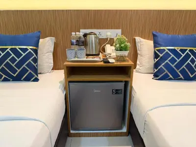a nightstand between two beds with a table between them at Astarr Hotel KL in Kuala Lumpur
