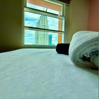 a bedroom with a bed and a window with a skyscraper at KLCC Sky suites apartment bukit bintang in Kuala Lumpur