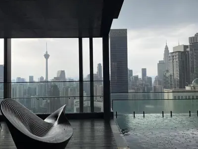 a chair in a room with a view of a city at IKON SUITE's A X O N BUKIT BINTANG in Kuala Lumpur
