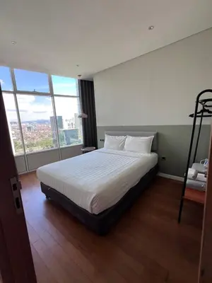 a bedroom with a bed with white sheets and windows at Sky suites klcc Family suites home in Kuala Lumpur