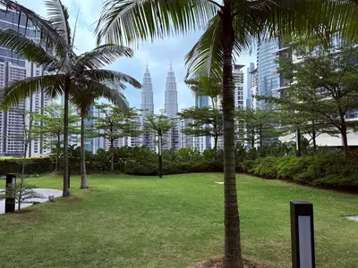 a park with palm trees and buildings in the background at IKON SUITE's E A T O N KLCC in Kuala Lumpur