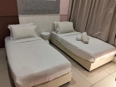 two beds in a room with white sheets and pillows at Family Suites at TRION KL in Kuala Lumpur