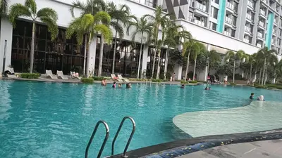 a swimming pool in front of a building with palm trees at Sky Residence at TRION KL in Kuala Lumpur