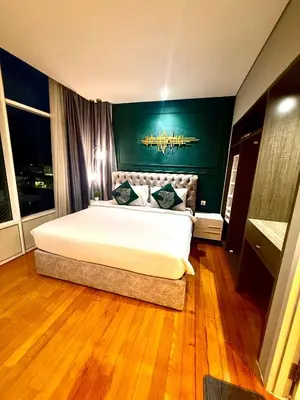 a bedroom with a large bed with a green wall at Sky Suites Klcc By Bukit Bintang in Kuala Lumpur