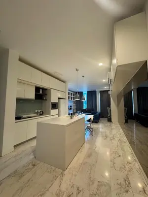 a large kitchen with white cabinets and a living room at Oras Suites At platinum KLCC in Kuala Lumpur