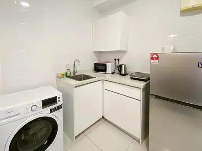 a white kitchen with a washing machine and a sink at Arte mont kiara by stayhold apartment in Kuala Lumpur