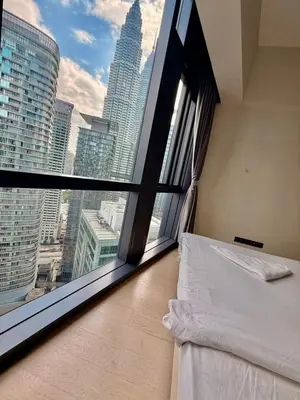a bedroom with a view of a city from a window at Good Residences at Star KLCC in Kuala Lumpur