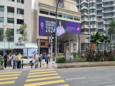 a group of people crossing a street in front of a building at Star KLCC Cosy Twin Tower Suite 2-3pax in Kuala Lumpur