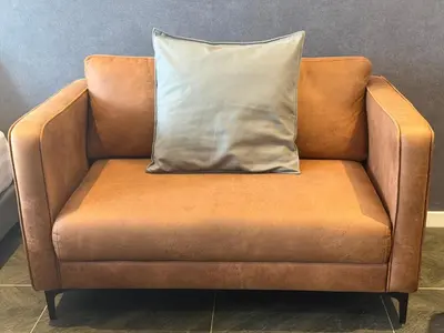 an orange chair with a pillow on top of it at Metahome at Scarletz suites KLCC in Kuala Lumpur
