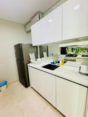 a kitchen with white cabinets and a black refrigerator at Vortex suites Near Klcc By I&J in Kuala Lumpur