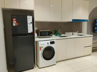 a kitchen with a washing machine and a microwave at Victoria Suites Quill Residence KLCC in Kuala Lumpur