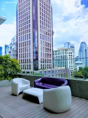 two chairs and ottomans on a balcony with buildings at Victoria Suites Quill Residence KLCC in Kuala Lumpur