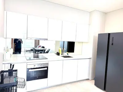a kitchen with white cabinets and a black refrigerator at Sky suites klcc by Aisyah in Kuala Lumpur