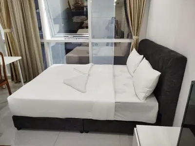 a bed with white sheets and pillows in a room at Binjai 8 KLCC BY Service Suites in Kuala Lumpur