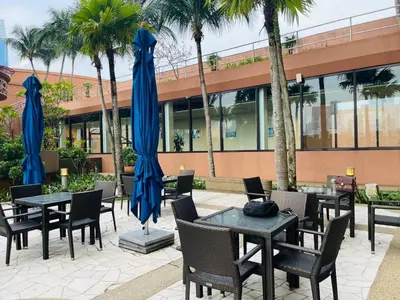 a patio with tables and chairs with blue umbrellas at Aurora Suites BUKIT At Times Square in Kuala Lumpur