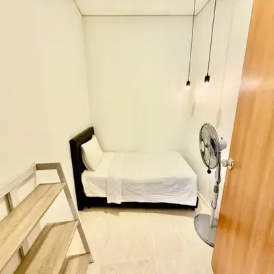 a small white bedroom with a bed and a fan at Klcc vortex suites by comfort stay in Kuala Lumpur