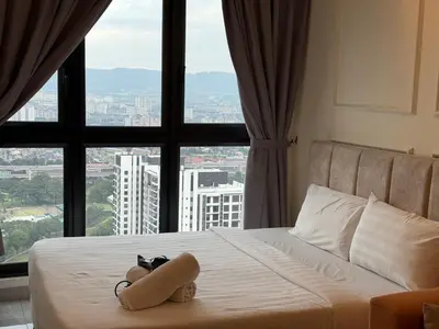 a bed with a teddy bear on it in front of a window at Bukit Bintang Suites KLCC by YBS in Kuala Lumpur