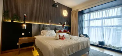 a bedroom with a bed with a desk and a window at pertama residency jacuzzi projector 120