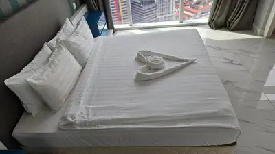 a white bed with a clock on top of it at Platinum Executive Suites Kuala Lumpur in Kuala Lumpur
