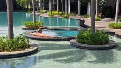 a man laying in a swimming pool at a resort at Trion KL Skyline Suites in Kuala Lumpur