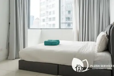 a bed in a room with a large window at Summer Suites Residences KLCC in Kuala Lumpur